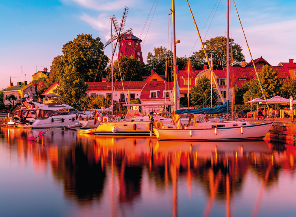 Kvällsbild över hamnmiljö Professionellt kvällsfoto över hamnmiljö med båtar och historisk bebyggelse.